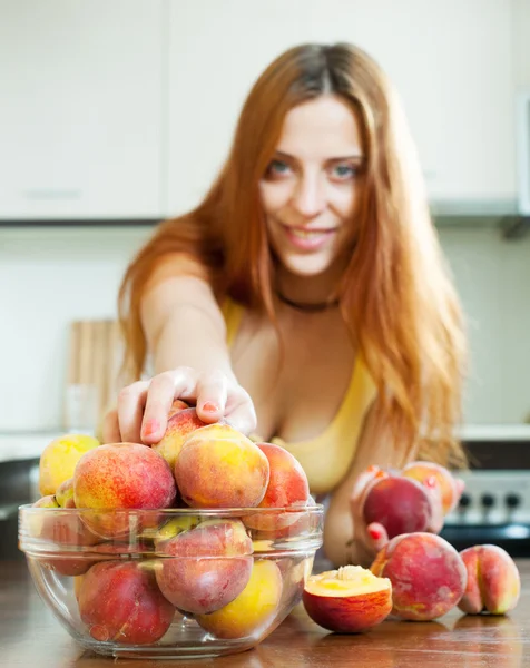 Girl taking peaches at home kitchen — Stock Photo, Image