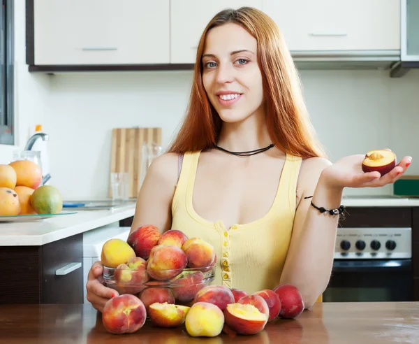 Mulher segurando pêssegos à mesa em casa — Fotografia de Stock