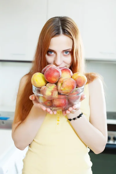 Long-haired girl in yellow holding peaches — Stock Photo, Image