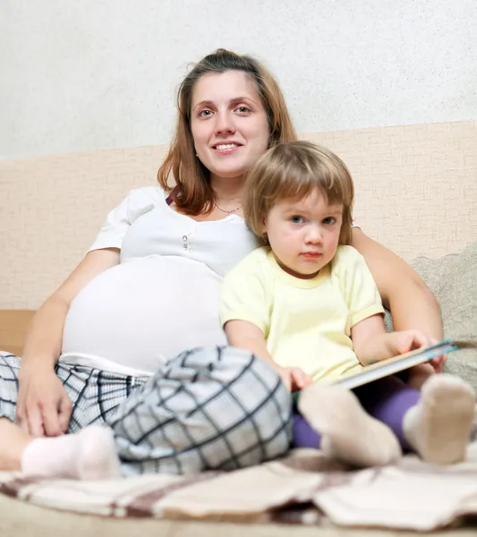 Mulher grávida e filha lê livro — Fotografia de Stock