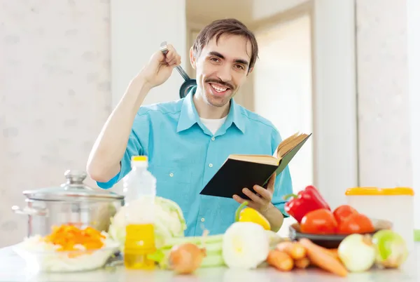 Homem panela concha e livro de receitas na cozinha — Fotografia de Stock
