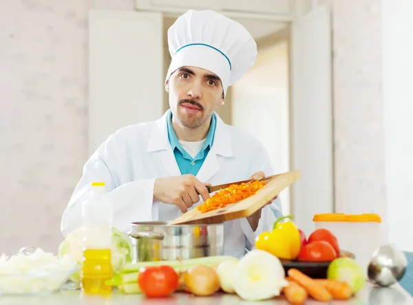 Cook in uniform works with vegetables — Stock Photo, Image