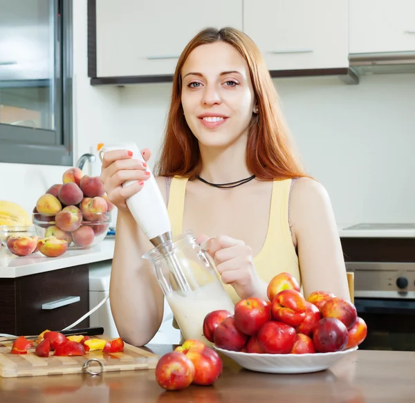Woman cooking dairy beverages with nectarines at kitchen — Stock Photo, Image