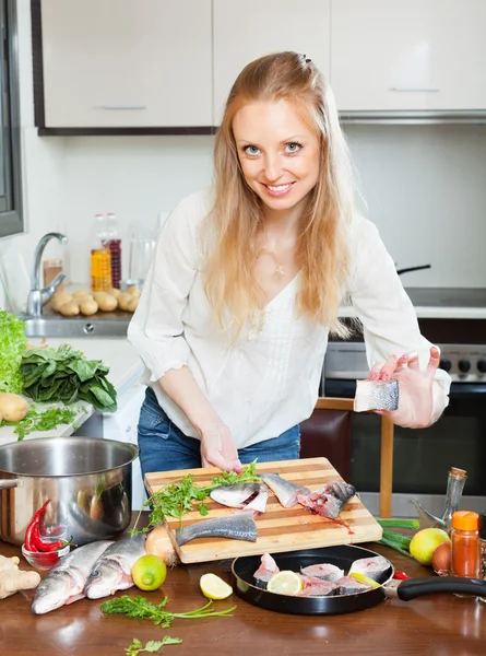 Woman putting sliced fish into frying pan — Stock Photo, Image