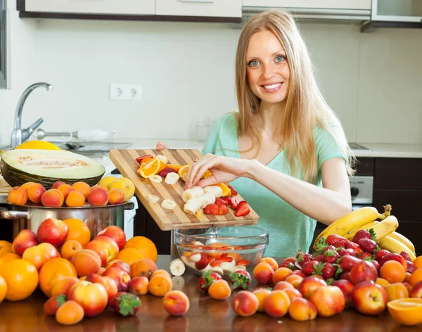 Счастливая блондинка готовит со спелыми фруктами — стоковое фото