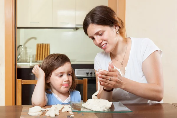 En tjej med sin mamma lär sig att forma degen figurer i hem — Stockfoto