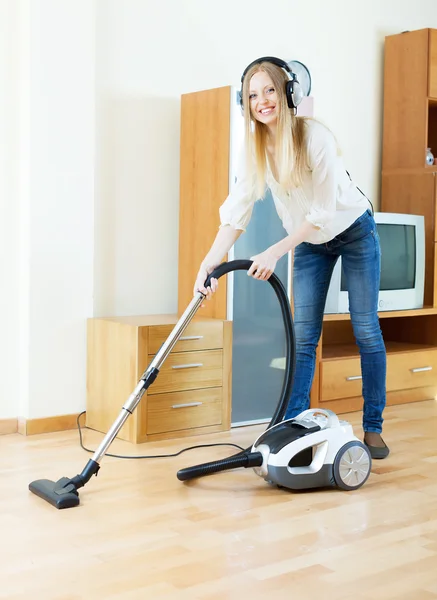 Cheerful blonde woman in headphones with vacuum cleaner — Stock Photo, Image
