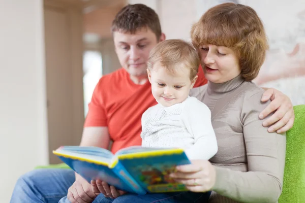 Padres con niño mira el libro —  Fotos de Stock