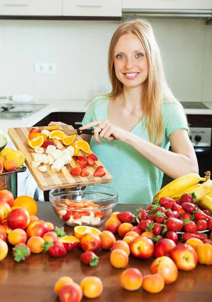 Mujer rubia feliz cortando frutas — Foto de Stock