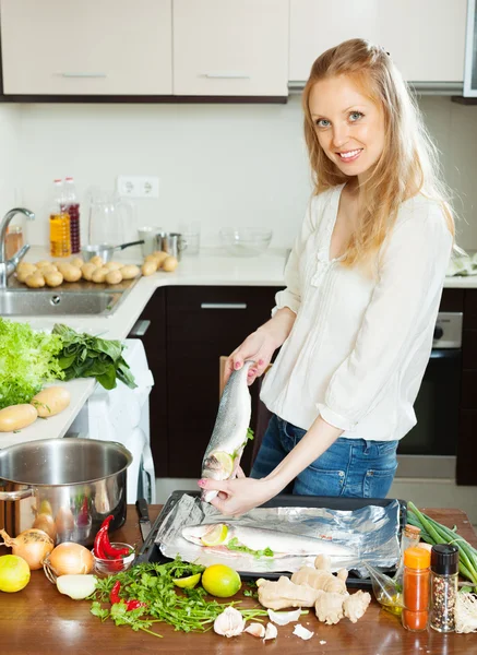 Donna Cheeful cucina pesce pieno — Foto Stock