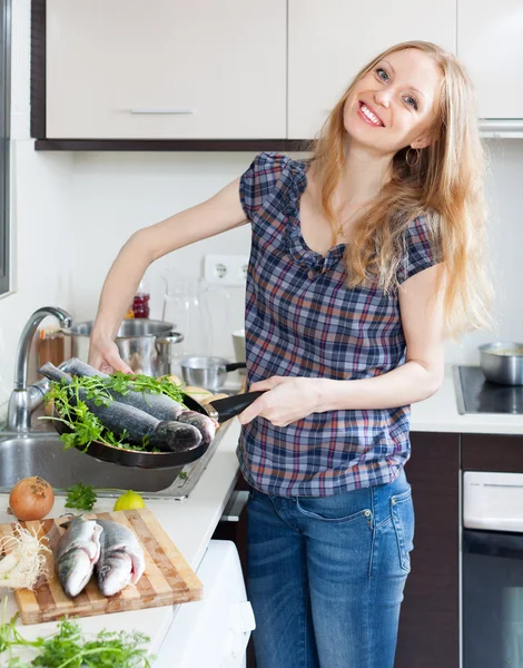 Positive girl with raw fish in frying pan — Stockfoto