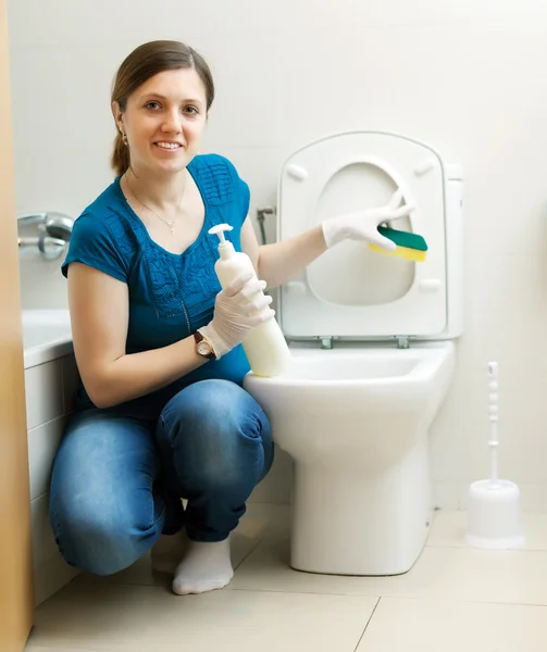 Улыбающаяся домохозяйка чистит унитаз губкой — стоковое фото