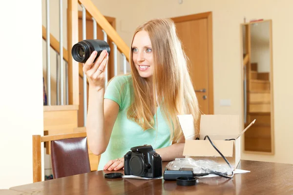 Mulher feliz desempacotar nova câmera digital e objetivo em casa um — Fotografia de Stock