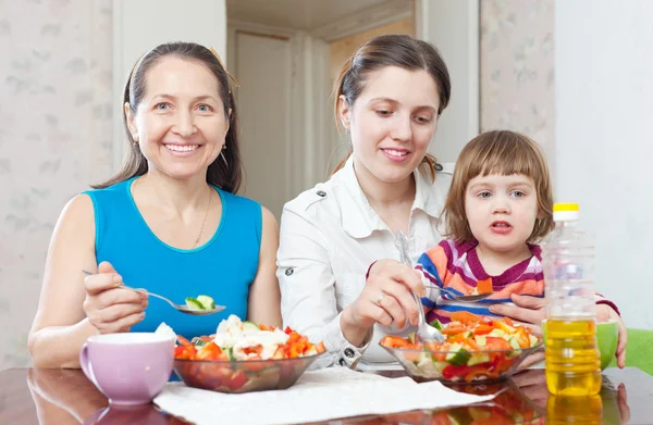 Women with girl eats vegetables salad — Stock Photo, Image