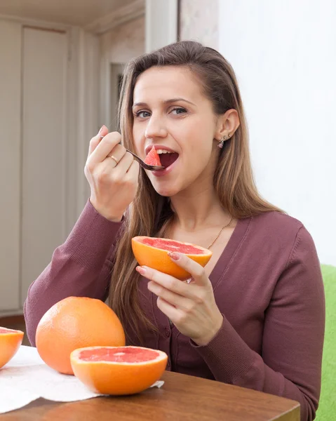 Ragazza mangia pompelmo con cucchiaio — Foto Stock