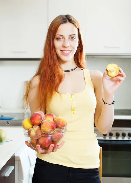 Houswife met perziken in kitchen — Stockfoto