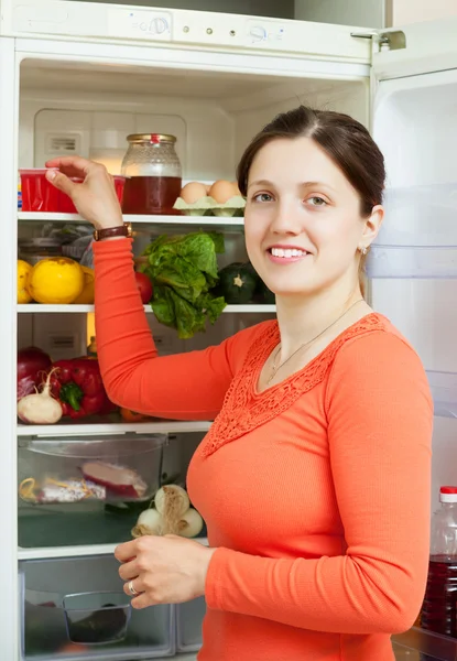 Mulher jovem à procura de algo na geladeira — Fotografia de Stock