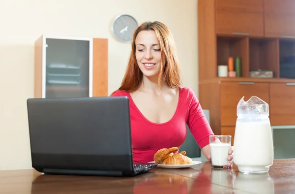 Jonge gelukkig roodharige meisje in roze laptop gebruikt tijdens breakfas — Stockfoto