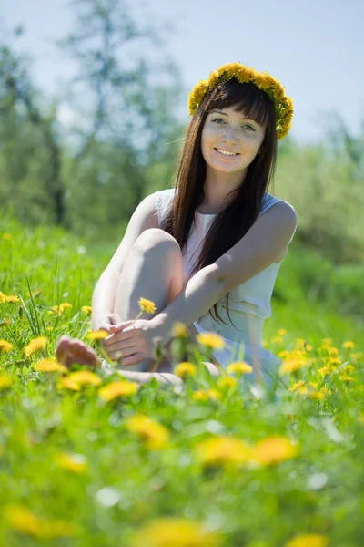 Happy girl sitting in dandelion meadow — Stock Photo, Image