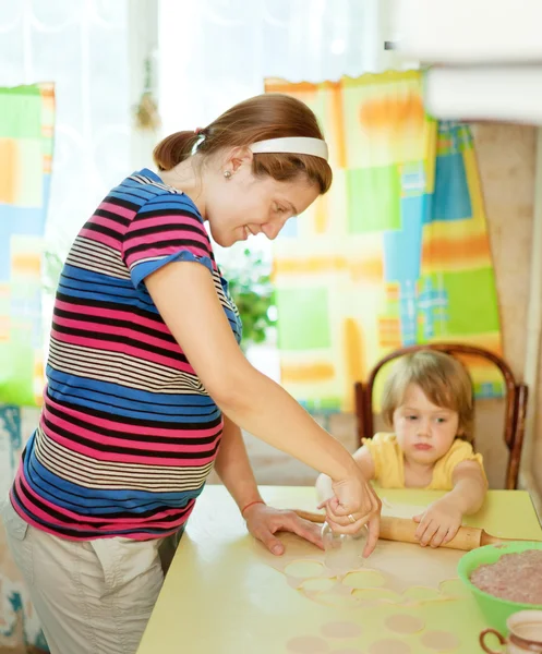 Těhotná žena s dítětem dělat knedlíky (pelmeni) — Stock fotografie