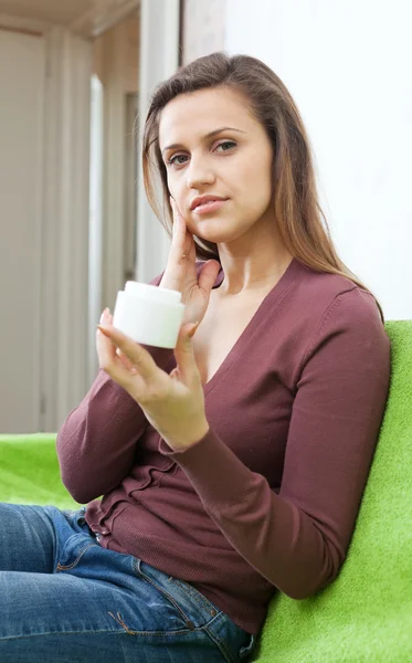 Vrouw zet crème op gezicht — Stockfoto