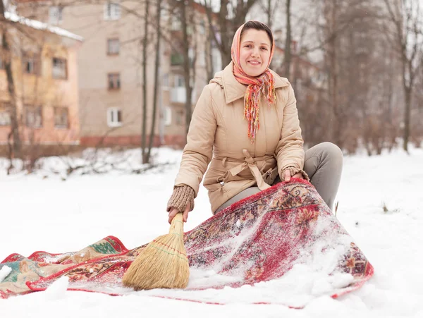 Mulher limpa tapete vermelho com neve — Fotografia de Stock