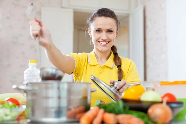 Mujer en cocina amarilla con cucharón — Foto de Stock