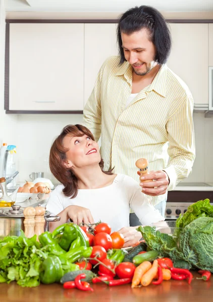 Young woman and man adding salt to the pot and in home kitchen — Stock Photo, Image