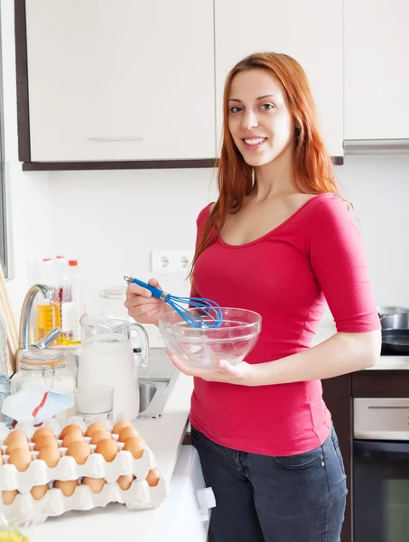 Mujer cocinando huevos revueltos con batidor — Foto de Stock