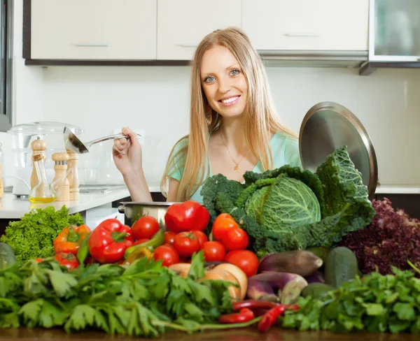 Happy blonde woman cooking with heap of vegetables — Stock Photo, Image