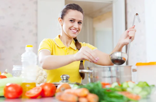 Happy woman salts the soup — Stock Photo, Image