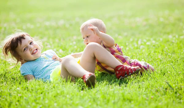 Šťastné děti hrají v trávě — Stock fotografie