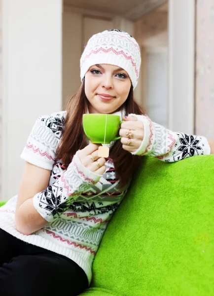 Woman in hat warms with cup of tea — Stock Photo, Image