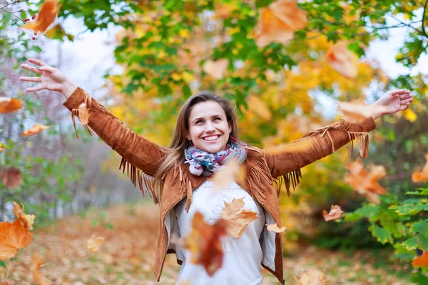 Happy woman throws autumn leaves — Stock Photo, Image