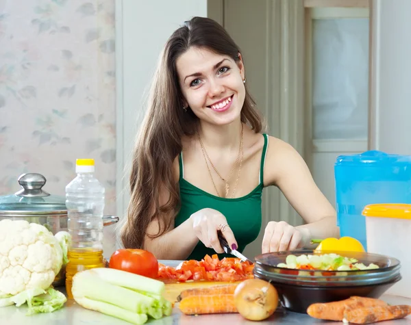 Beautiful housewife cuts tomato — Stock Photo, Image