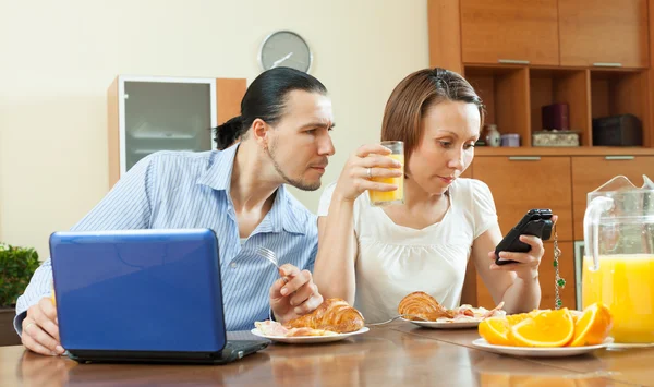 Casal usando dispositivos durante o café da manhã — Fotografia de Stock