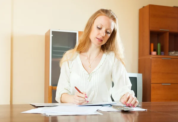 Une femme aux cheveux longs sérieuse remplit des documents financiers — Photo