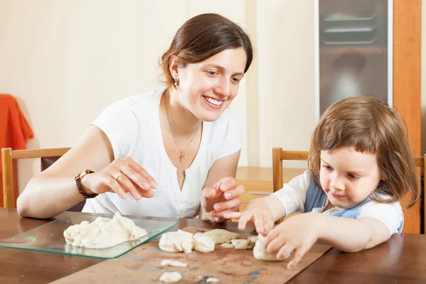 Young woman and her child sculpting from clay or dough in home — Stock Photo, Image