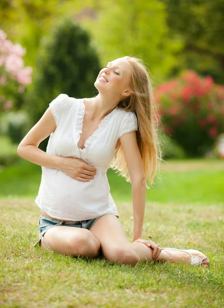 Pregnant woman relaxing on grass — Stock Photo, Image