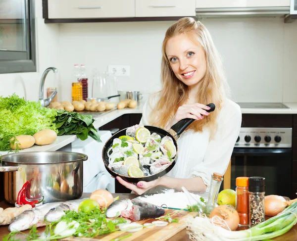 Chica sonriente cocinando pescado en harina en sartén — Foto de Stock