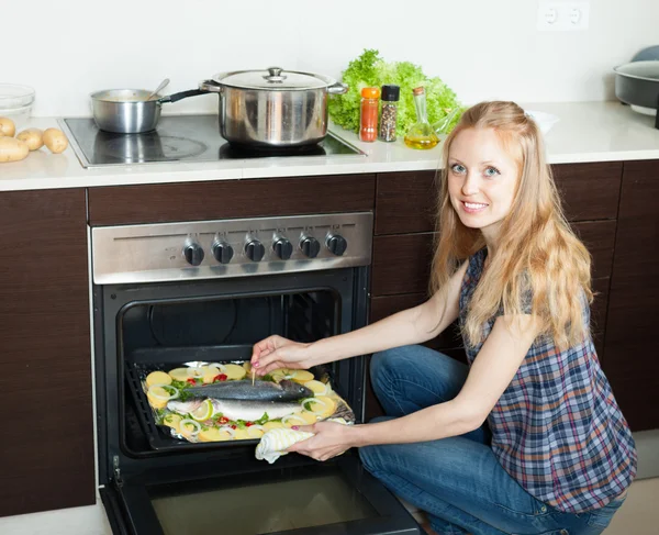 积极的家庭主妇烹饪烤箱里的生鱼 — 图库照片