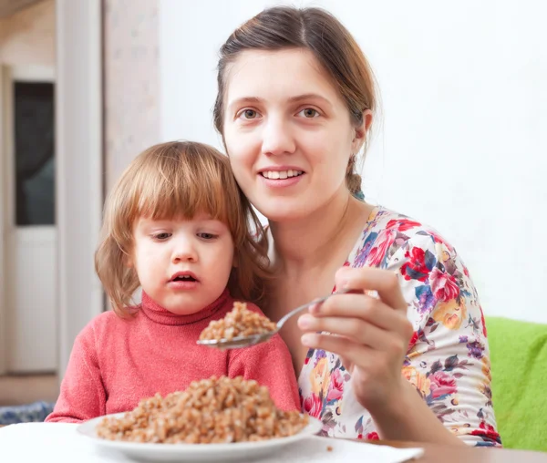 Donna con bambino mangia grano saraceno — Foto Stock