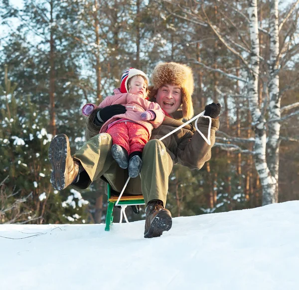 Счастливый мужчина с ребенком катается на санках — стоковое фото