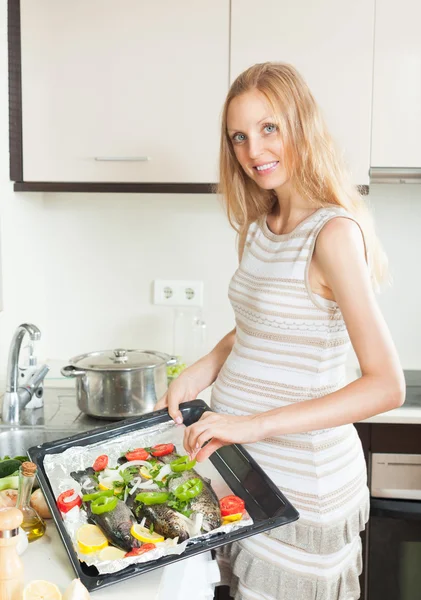 Lachende vrouw paprika aanbrengend vis op huis keuken — Stockfoto