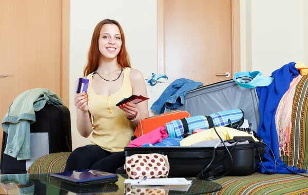 Femme assise sur le canapé et valise d'emballage — Photo