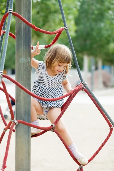 Girl in dress climbing on ropes — Stock Photo, Image