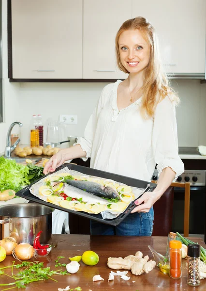 Kvinnan matlagning fisk med potatis i stekpanna — Stockfoto