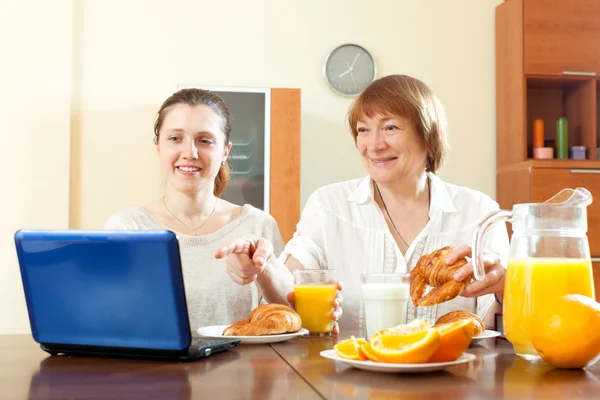 Mujeres buscando e-mail en el ordenador portátil durante el desayuno — Foto de Stock