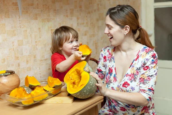 Happy mother with child cooks pumpkin — Stock Photo, Image
