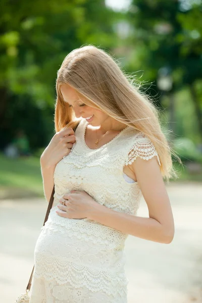 Uśmiechający się kobieta w ciąży w parku — Zdjęcie stockowe